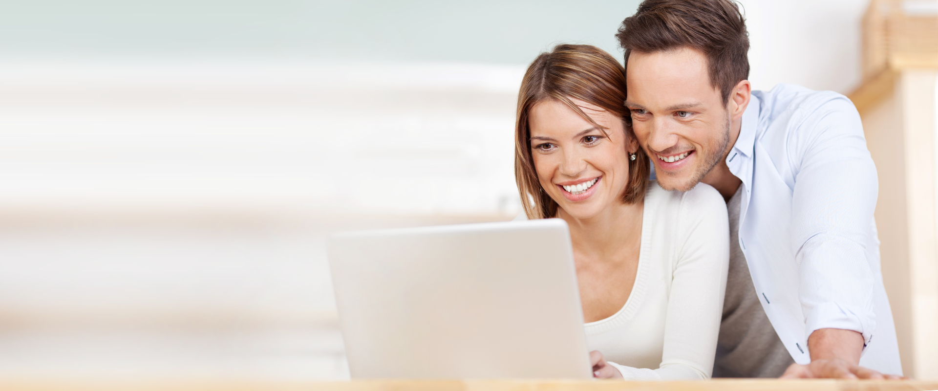 Junges Paar, Mann und Frau, schauen in einen Laptop